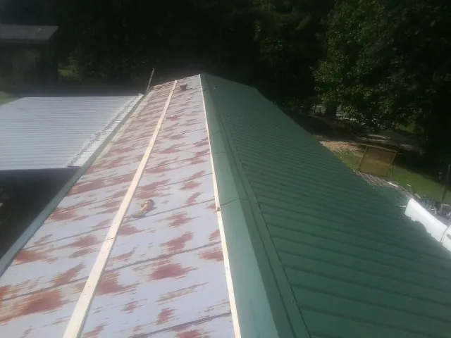 Old rusted panels beside newly installed green metal roofing — Wind Damage Roof Repair by Roofing Brothers in Westport Point