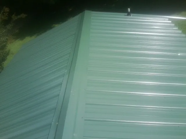 New green metal panels meeting at the ridge of a roof — Flat Roof Repair work by our crew in Westport Point