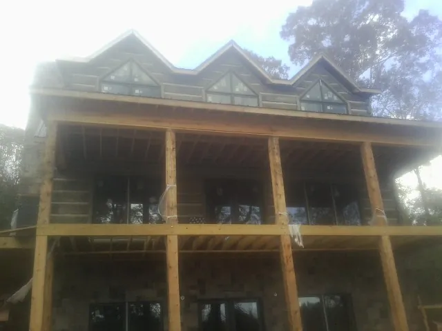 Dormers and porch framing on a large log home under construction — Roof Coating work by our crew in Westport Point