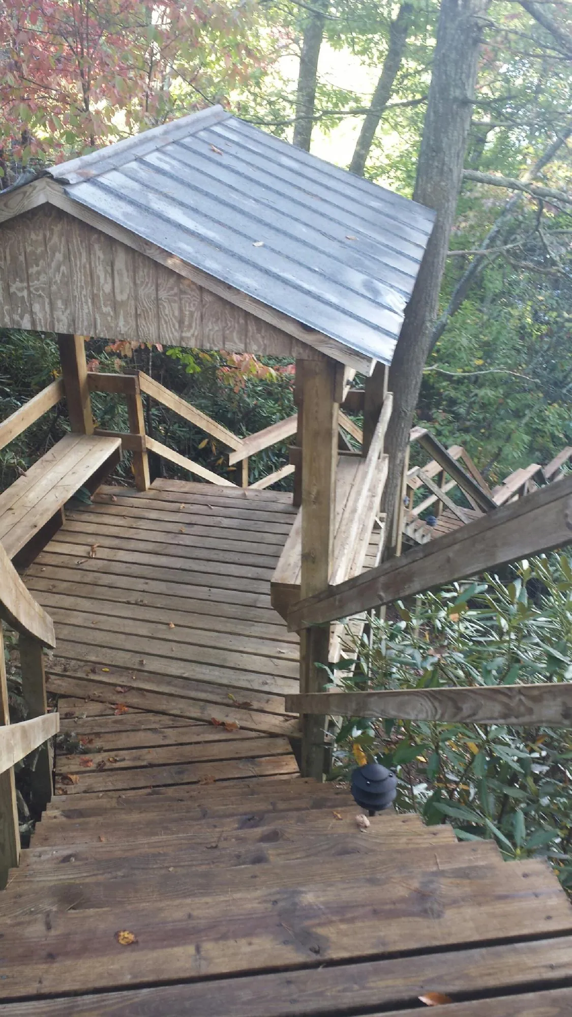 Metal roofed shelter over wooden steps on a wooded walkway — Skylight Repair & Installation work by our crew in Westport Point