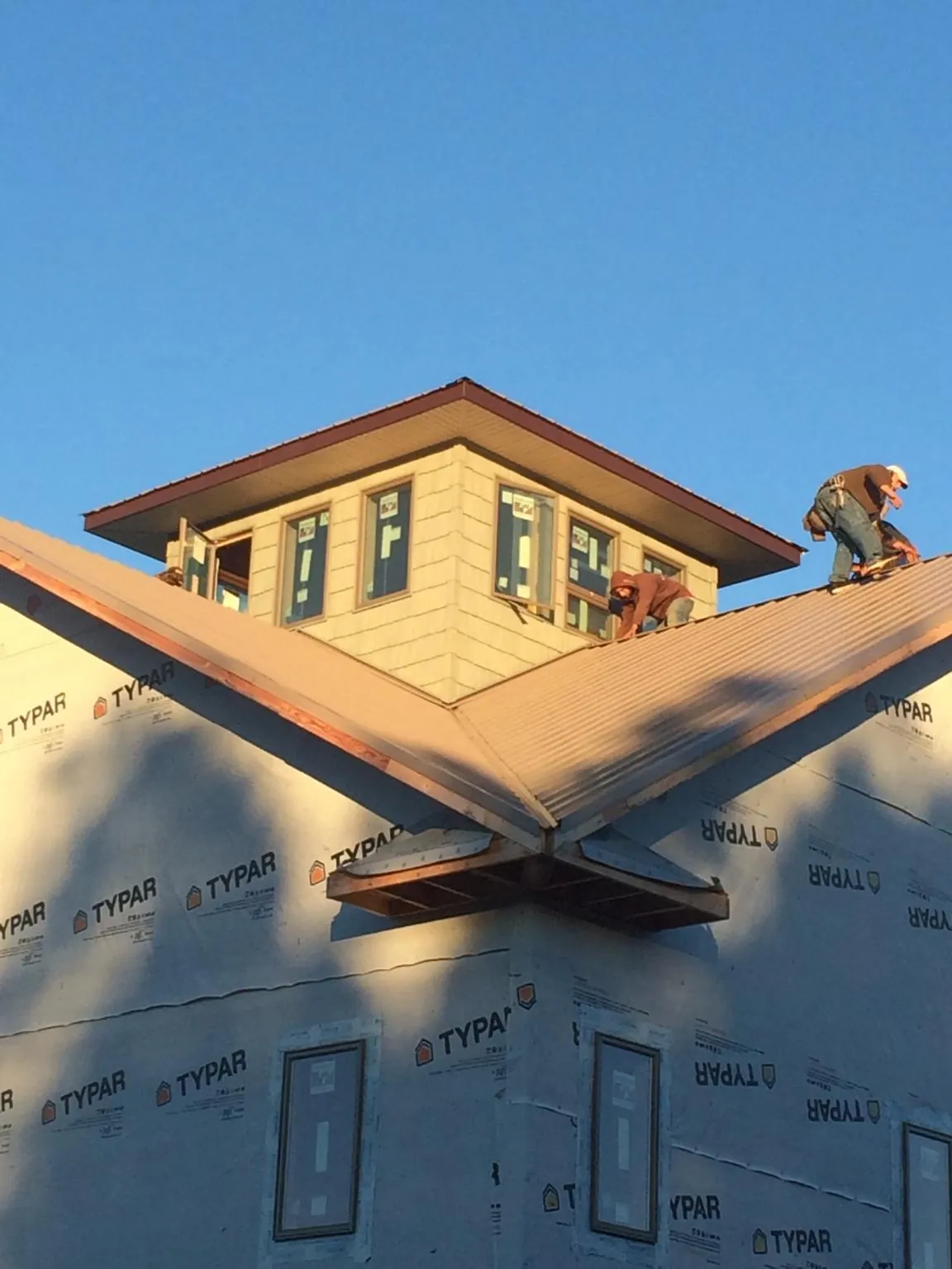 Roofers working around a rooftop cupola on a new metal roof at sunset — Roof Waterproofing in Westport Point by Roofing Brothers